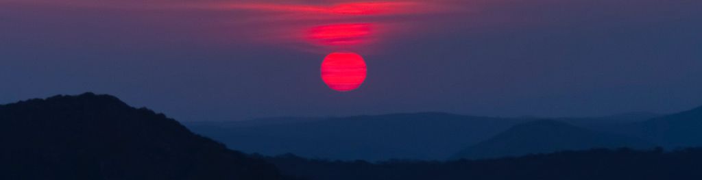 Sun setting in red sky over mountains. Photo Bashar Alaeddin