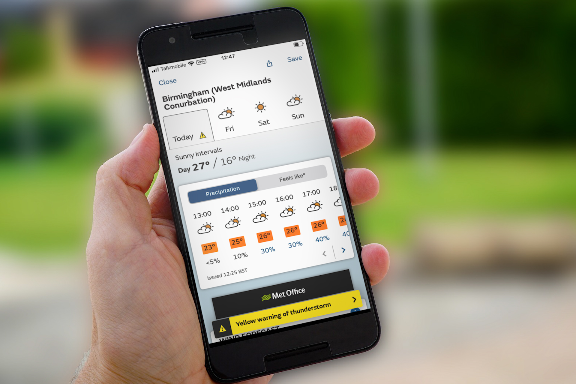 Hand holding mobile phone showing Met Office weather weather on screen