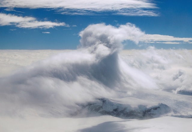 Dramatic, towering cloud forming above a mountain range because of the foehn effect.